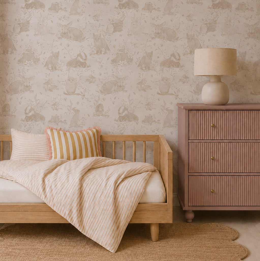 Minimalist bedroom with a light wooden bed, striped bedding, round woven rug, mauve dresser with lamp, and Woodland Wonder Wallpaper, Neutral—featuring a subtle animal pattern. The soft, neutral color palette creates a calm atmosphere.