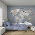 A cozy kids room with a blue bed and striped walls, featuring the World Map Mural, Blue—illustrated with animals and landmarks for each continent—to bring geography to life in a playful, educational way.