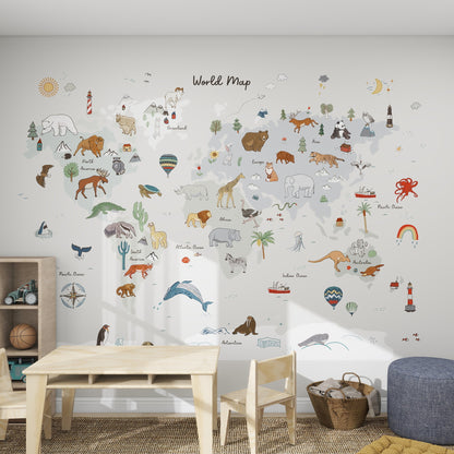 Children’s playroom with a cozy setup featuring the World Map Mural, Grey—an educational wallpaper illustrated with animals and landmarks. A small table, rug, toys, pouf, and shelves complete this inviting kids’ room.